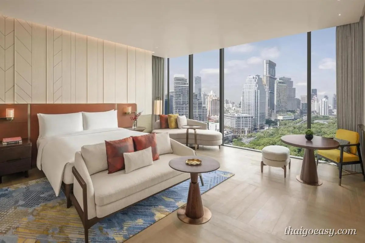 Andaz One Bangkok 客房，白色大床與長沙發，落地窗外是公園綠地與市區