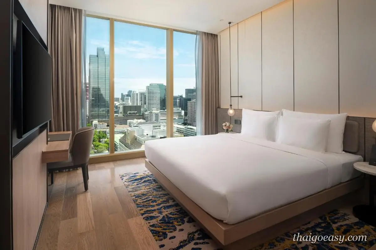 Grand Nikko Bangkok Sathorn 客房，大床與木質書桌，落地窗外是沙吞市景
