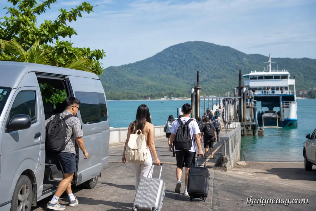 東岸島嶼渡輪碼頭，旅客拖著行李從接駁廂型車走向渡輪，背景是山與海