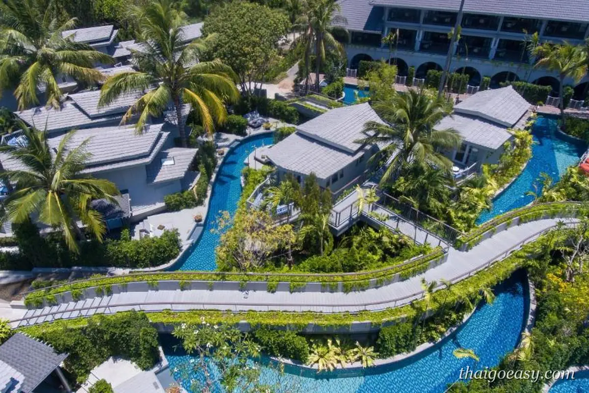 空拍 Melia Koh Samui，蜿蜒的帶狀長泳池穿過灰瓦屋頂的別墅群與椰林