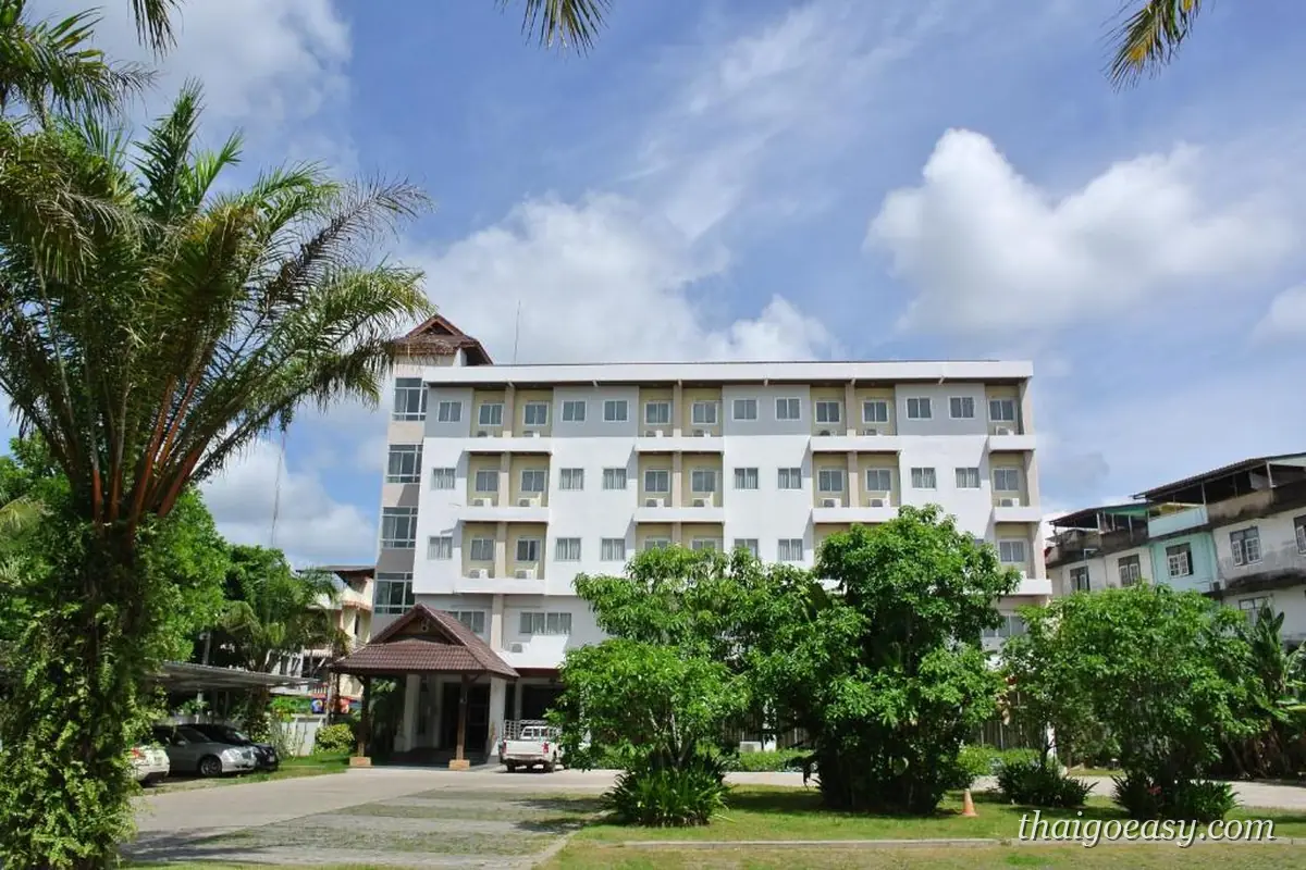 Nana Buri Hotel 白色五層樓外觀與入口車道，前方是椰子樹與綠籬