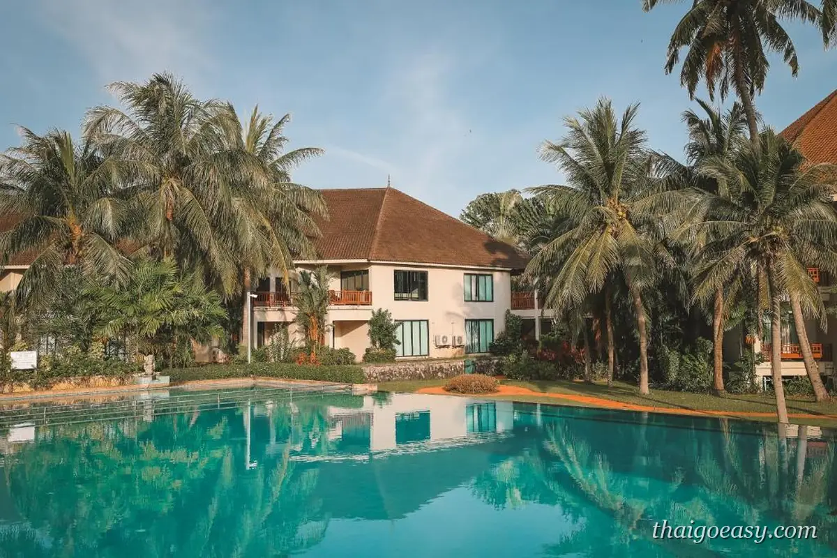 The Nouveau Chumphon Beach Resort 的泳池與紅瓦客房樓，椰林環繞