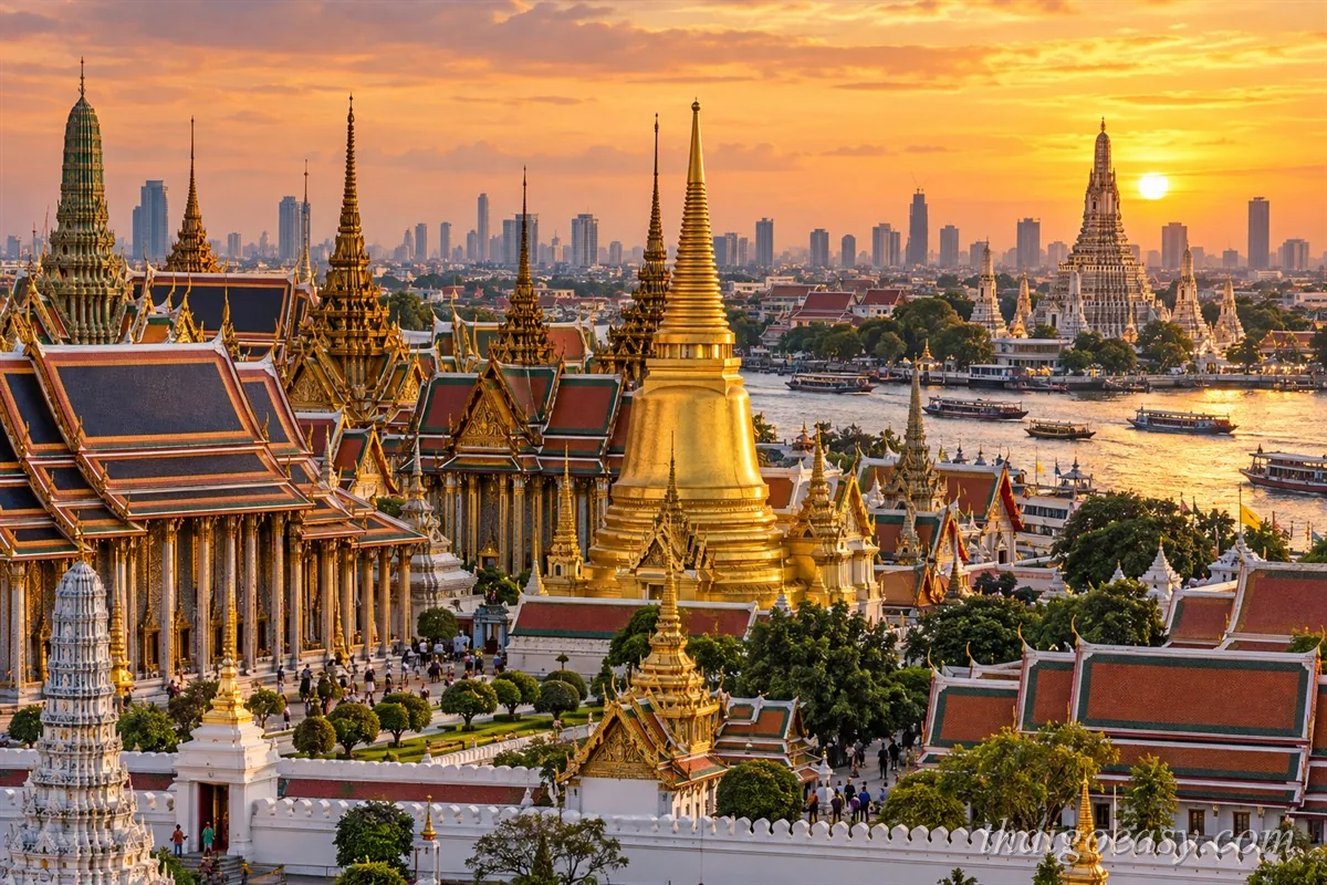 曼谷景點空拍：前景大皇宮與玉佛寺的金色舍利塔群，中景昭披耶河上的船隻，右側鄭王廟剪影正對落日，背景是曼谷市區天際線